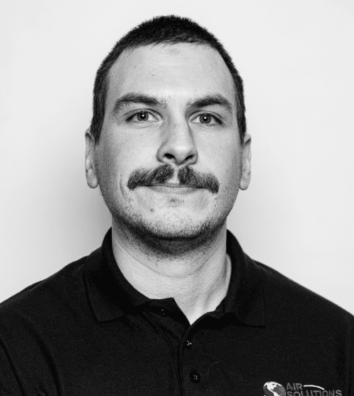 A man with a mustache is wearing a black collared shirt with the logo "Air Solutions." He is facing the camera against a plain white background.