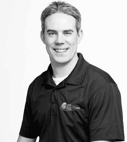 Man wearing a short-sleeved polo shirt with an "Air Solutions" logo, smiling at the camera in a black and white portrait.