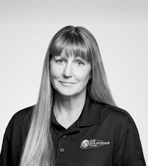 A woman with long straight hair is wearing a dark “Air Solutions Canada” polo shirt, looking at the camera with a neutral expression against a plain light background.
